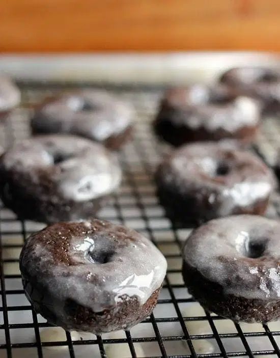 chocolate donuts with icing on a cooling rack