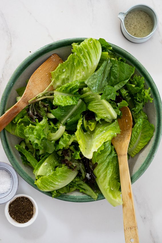 a bowl filled with lettuce and wooden spoons