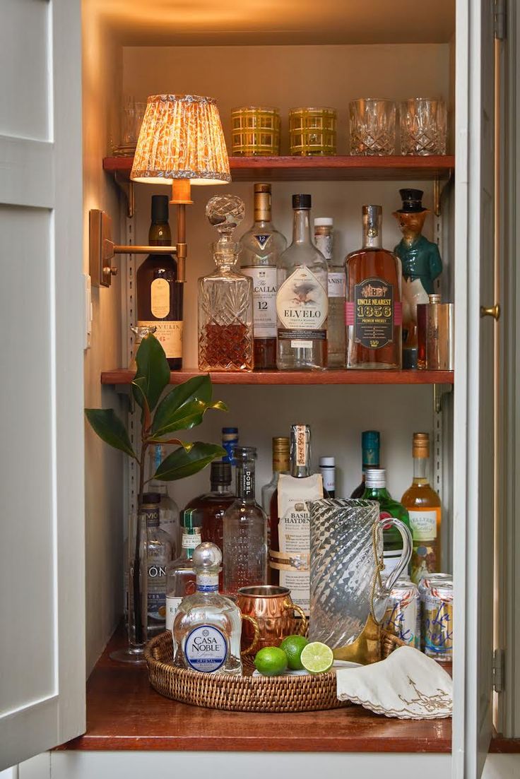 an open cabinet filled with liquor bottles and other alcohol on top of a wooden table