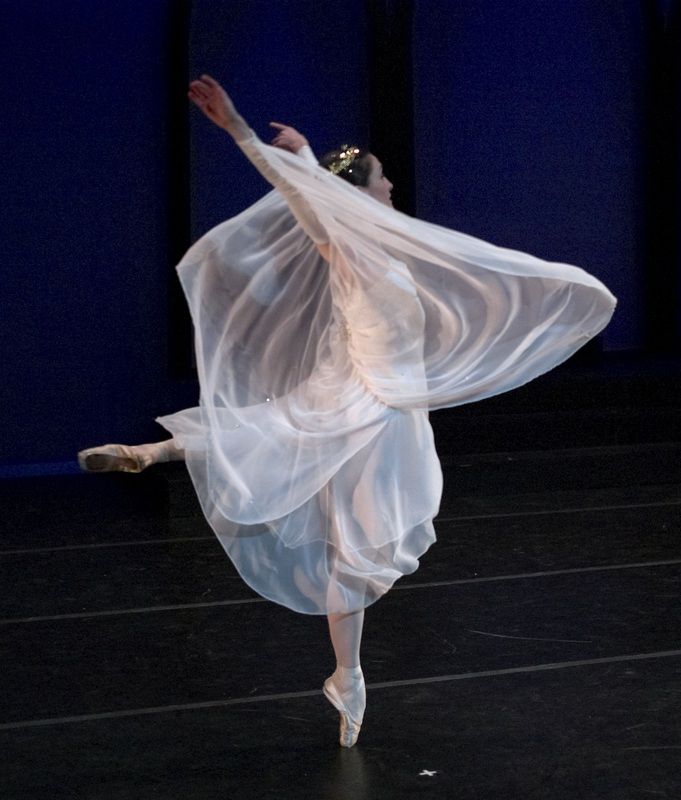 a ballerina in white is dancing on stage with her arms spread out to the side