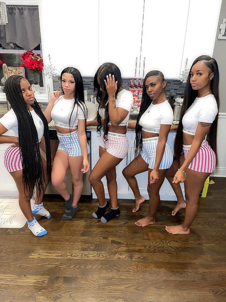 six women in short shorts and white shirts posing for the camera with their hands on their face