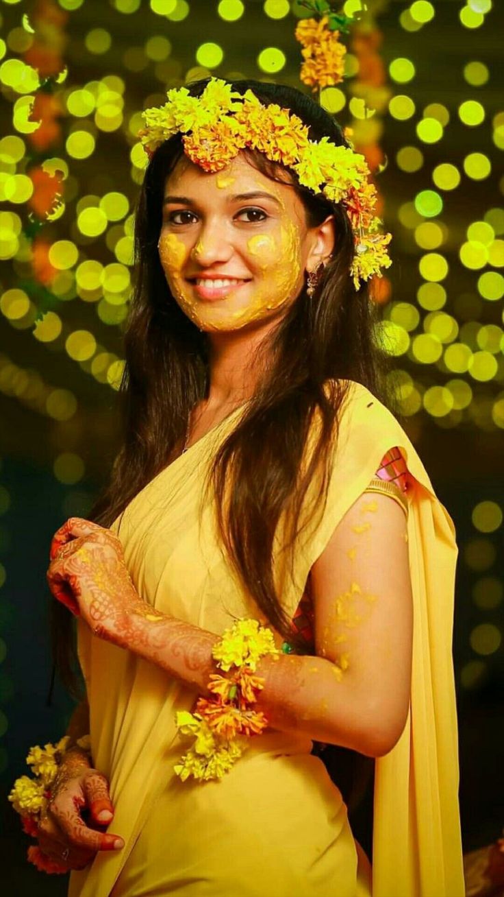 a woman with yellow paint on her face and flowers in her hair is smiling at the camera