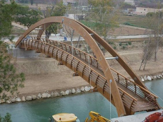 a wooden bridge over a river next to a construction site