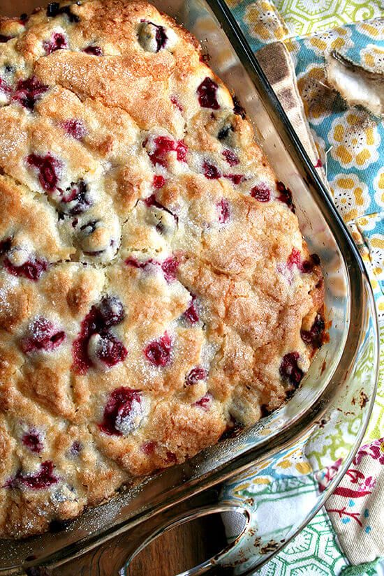 a blueberry cobbler in a glass dish on a table with utensils