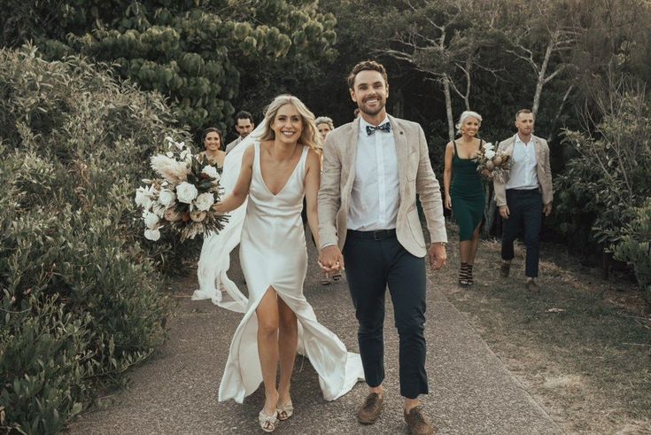 a man and woman walking down a path holding hands