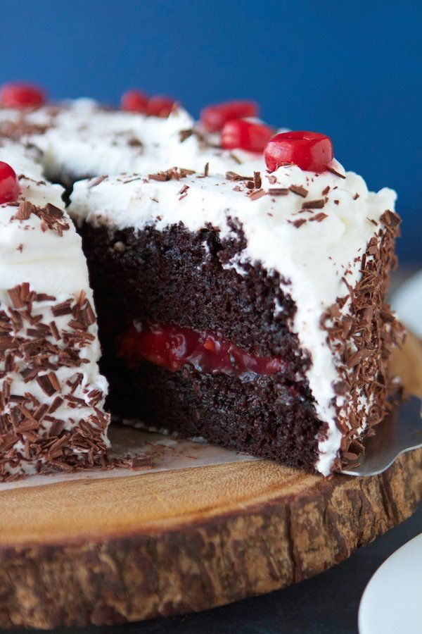 a piece of chocolate cake with white frosting and cherries on the top slice