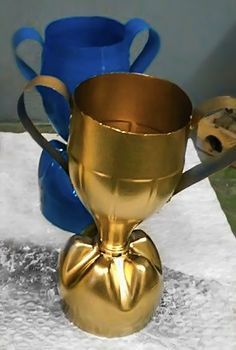 a gold cup sitting on top of a table next to a blue vase and spoon