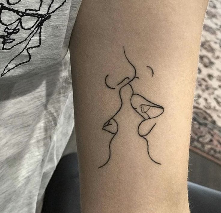 a woman's arm with a tattoo on it that has a line drawing of two people