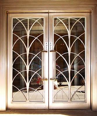 the front door to a building with an iron design and glass panels on it's sides