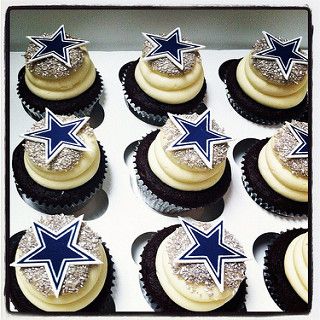 cupcakes with white frosting and blue stars on top are arranged in a box