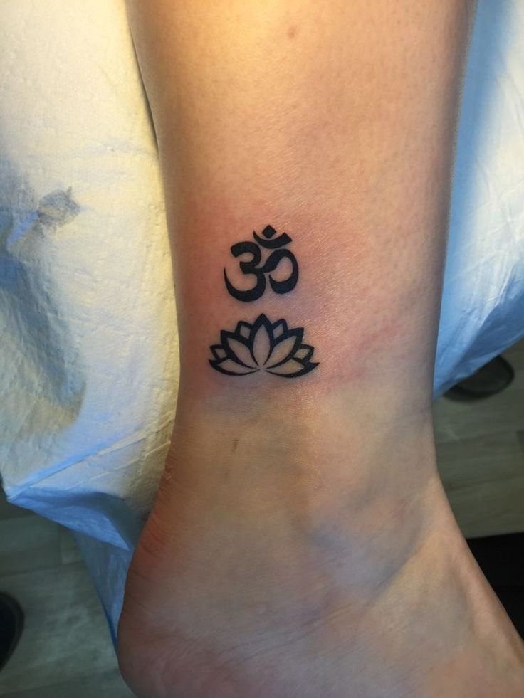 a small tattoo on the ankle of a person with a lotus flower in front of it