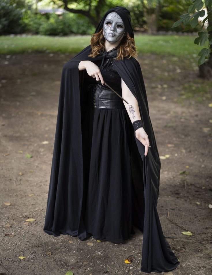 a woman dressed as a skeleton in a black dress with a white face paint on