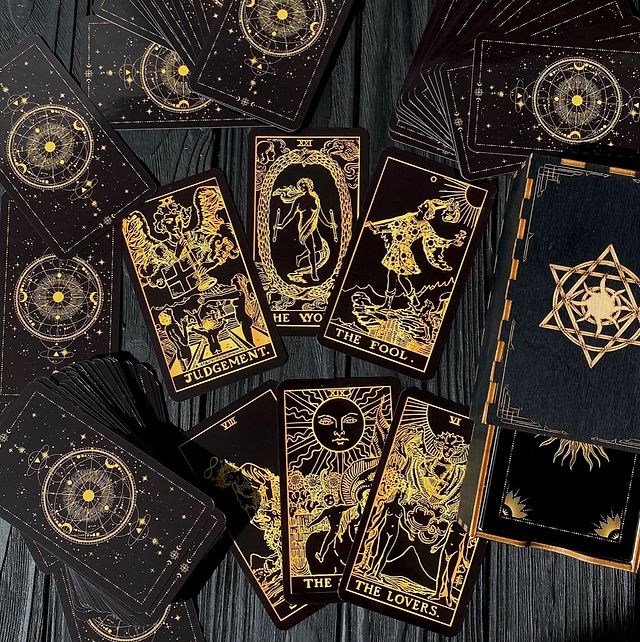 several tarot cards with gold designs on them sitting on top of a wooden table