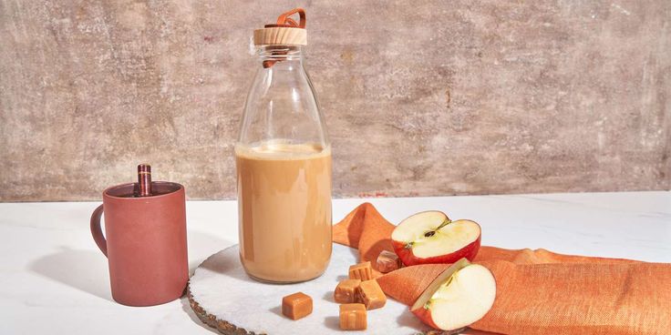 an apple cider, cinnamons and apples on a plate next to a bottle