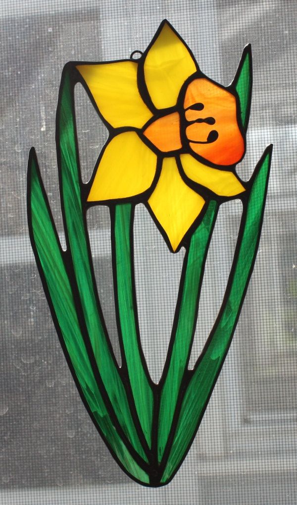 a stained glass daffodil flower on a window sill