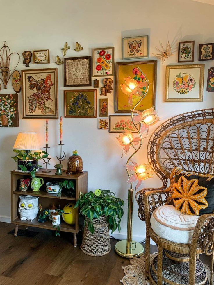 a living room filled with lots of framed pictures and plants on the wall next to a wicker chair