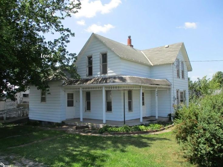 an old white house sitting in the grass