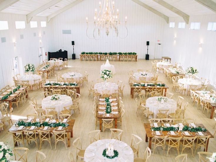 a room filled with tables and chairs covered in white tablecloths next to a chandelier