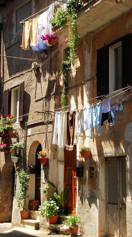 clothes hanging out to dry in front of an old building with flowers and potted plants