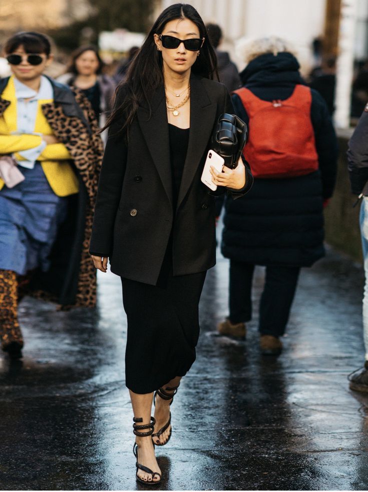 a woman walking down the street with an umbrella in her hand and other people behind her