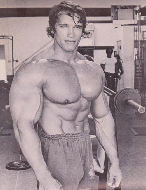 a man with no shirt is posing for the camera while holding a barbell in his hand