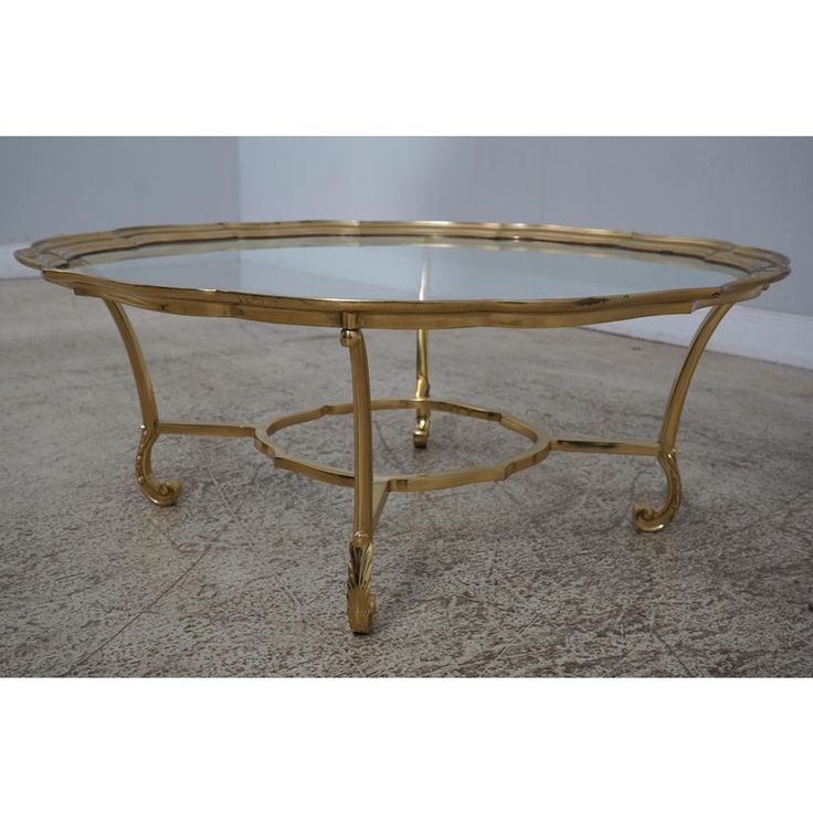 a gold coffee table with glass top and metal legs, on carpeted flooring