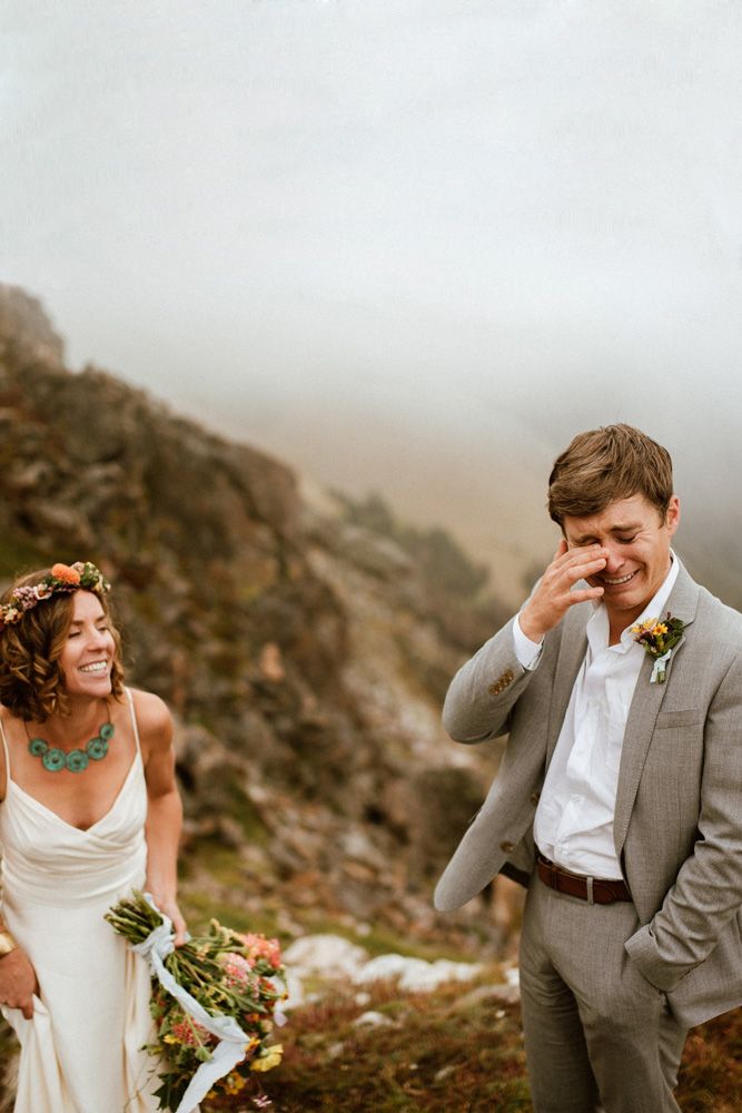 a man and woman standing next to each other in front of a mountain with flowers on their head