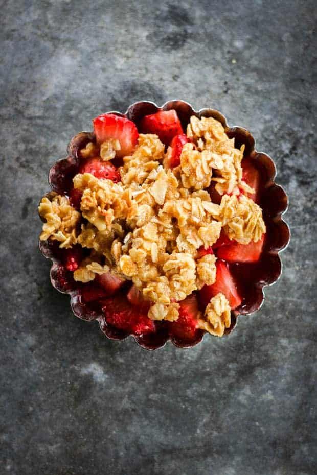 a bowl filled with granola and strawberries sitting on top of a gray surface