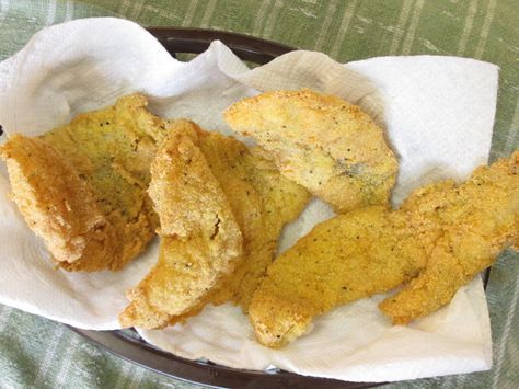 fried fish fillets in a basket on top of a tablecloth with napkins