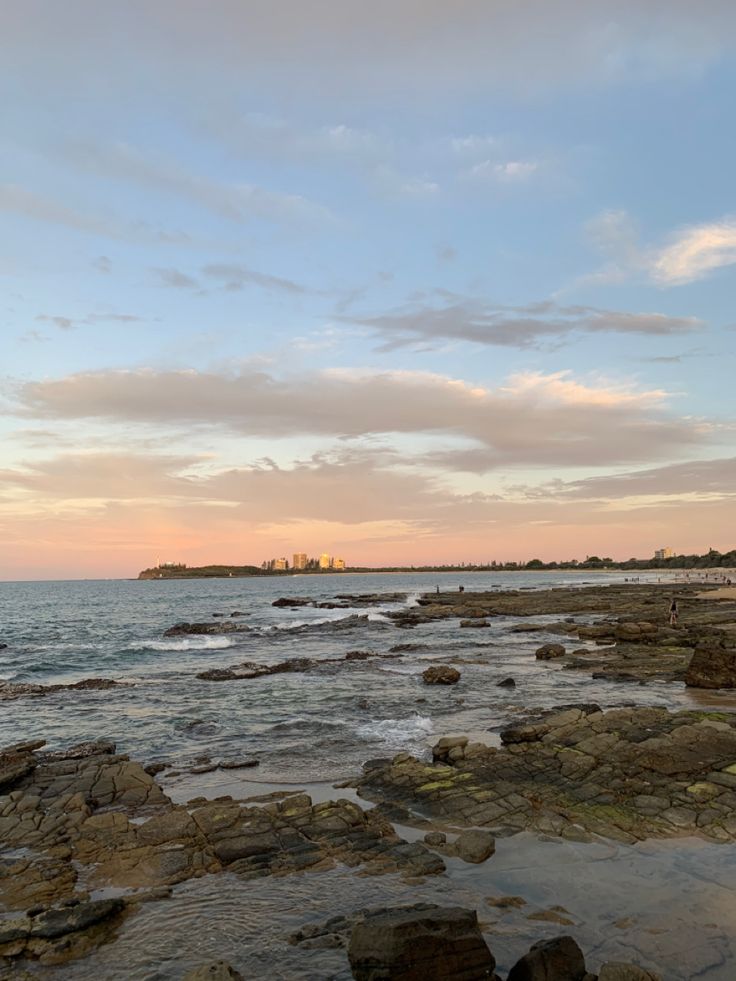 the ocean with rocks and water at sunset