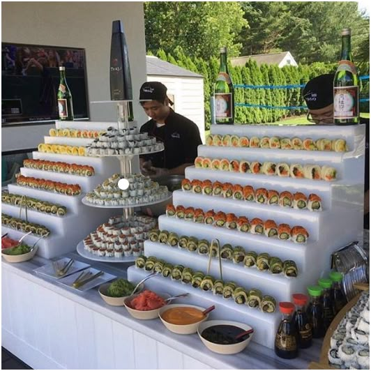 two men standing behind a table with food on it