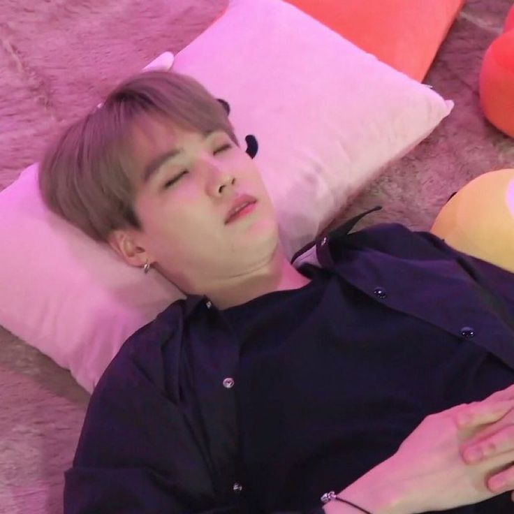 a young man laying on the floor next to pillows