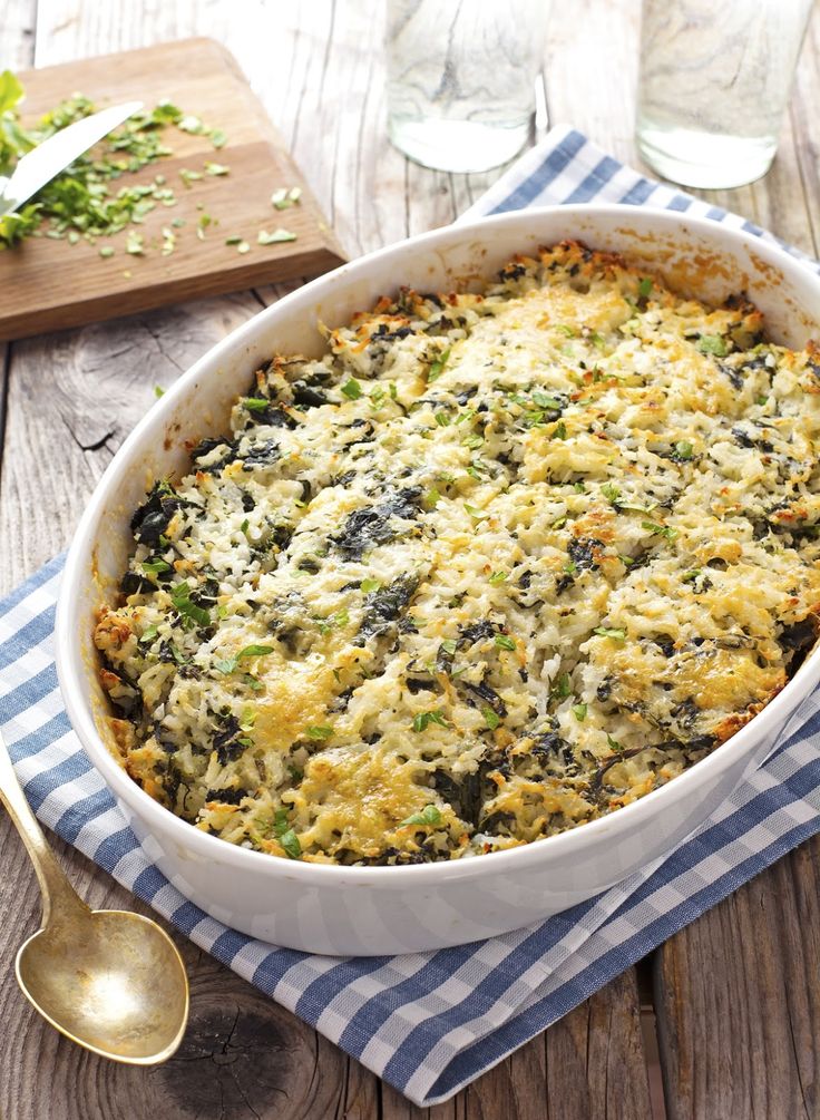 a casserole dish with spinach and cheese in it on a wooden table