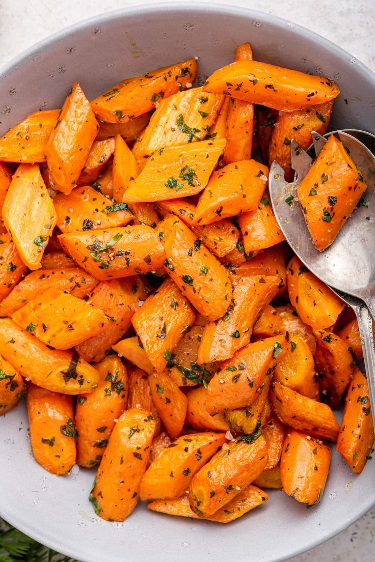 a white bowl filled with cooked carrots and herbs