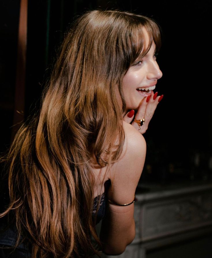 a woman with long brown hair and red nail polish on her nails is posing for the camera