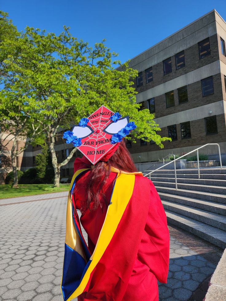 a woman with red hair wearing a colorful hat on top of her head in front of a building