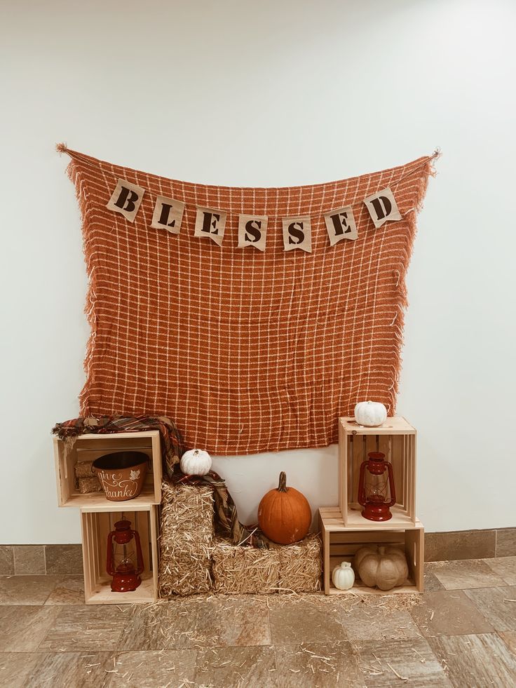 a display with pumpkins and other items in crates on the floor next to a wall