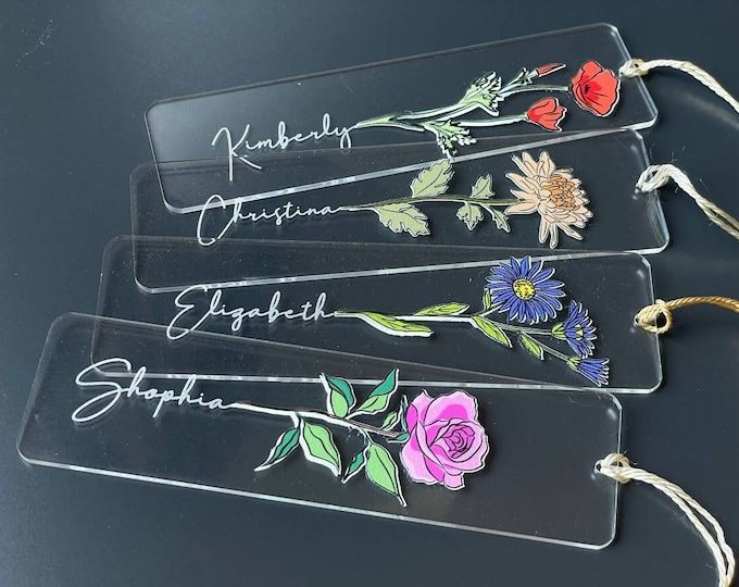 three glass tags with flowers on them sitting on a table