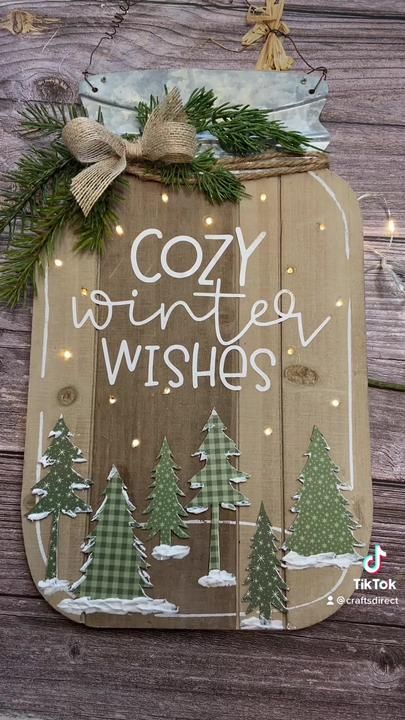 a wooden sign that says cozy winter wishes with trees in the snow and lights around it