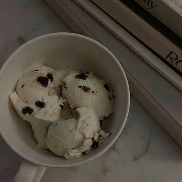 three scoops of ice cream with chocolate chips in a white bowl on a marble counter