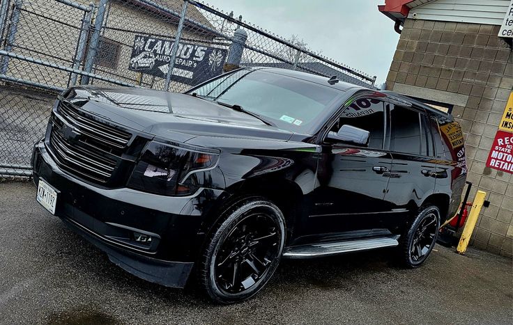 a black suv parked in front of a fence