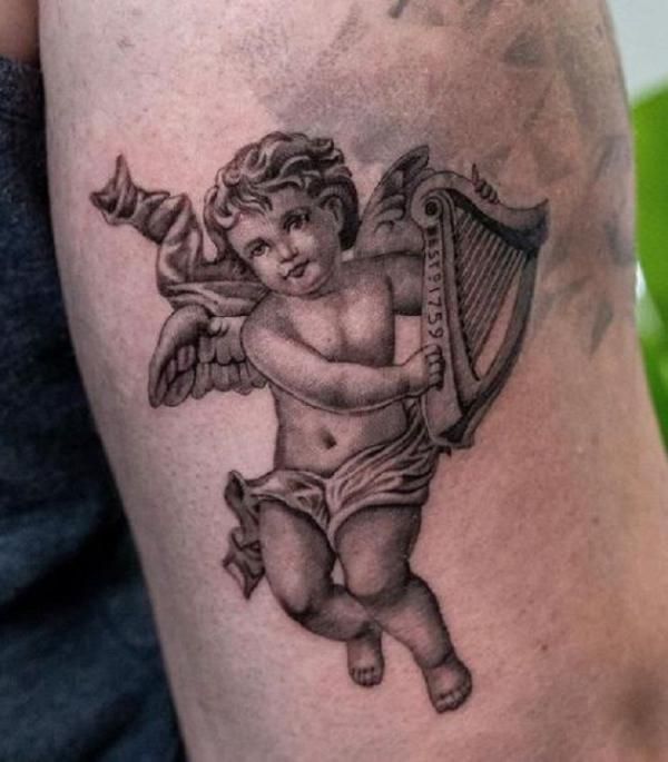 an angel with a harp tattoo on his arm is shown in black and grey ink