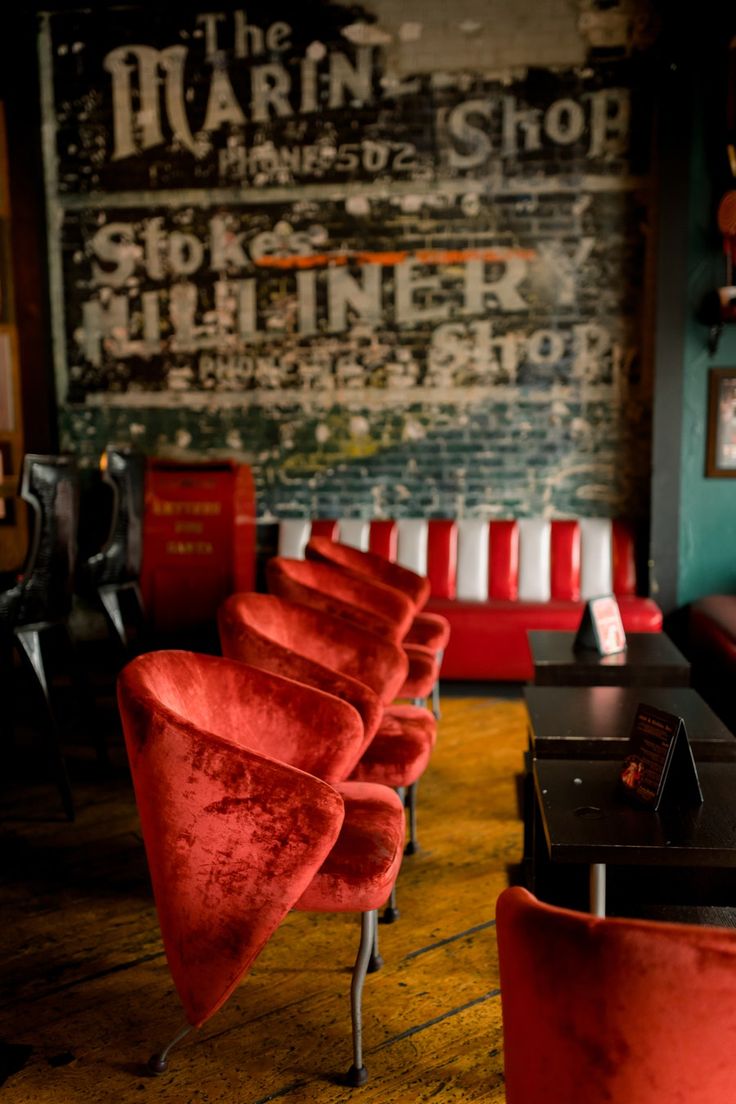 a row of red chairs sitting next to each other on top of a wooden floor