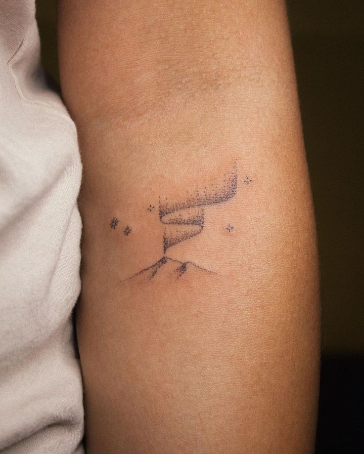 a woman's arm with a tattoo on it that has stars in the sky