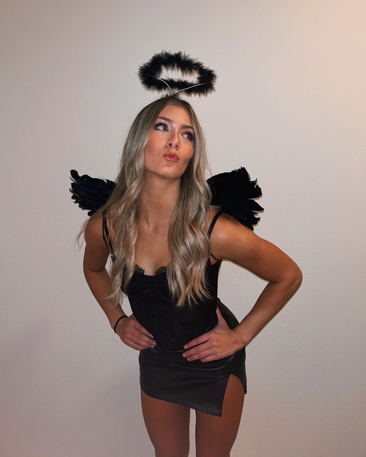 a woman in a black dress with angel wings on her head posing for the camera