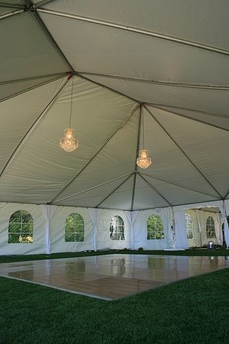 a large white tent with chandeliers hanging from it's ceiling and windows