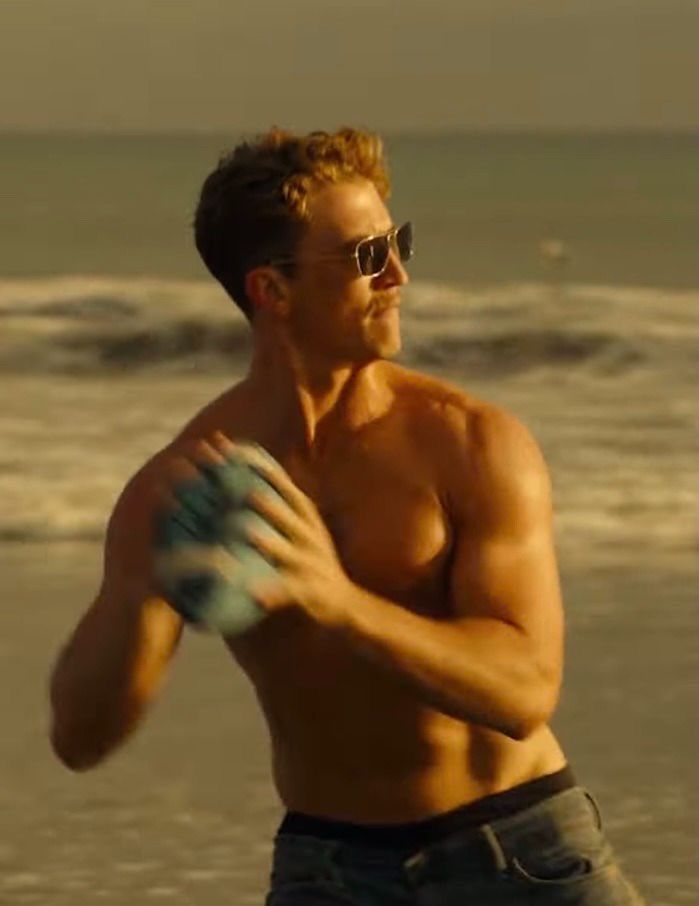 a shirtless man holding a frisbee on the beach