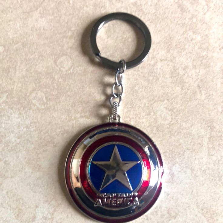 the captain's shield keychain is hanging from a metal ring on a marble surface