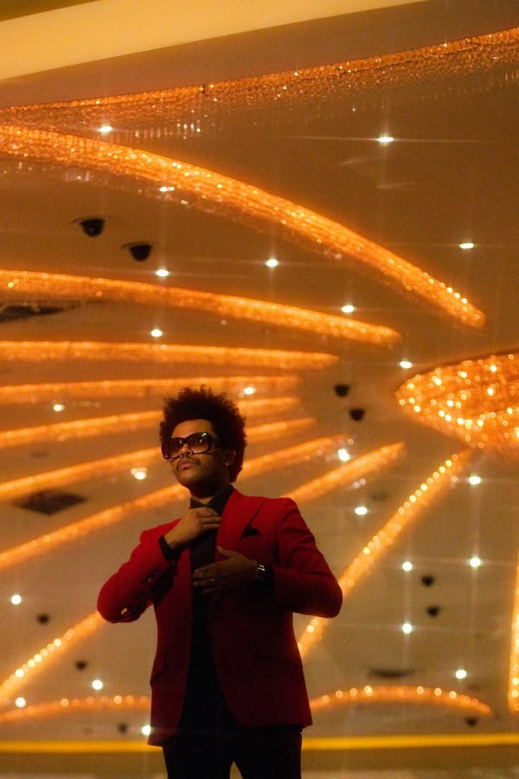 a man standing in front of a chandelier with lights hanging from the ceiling