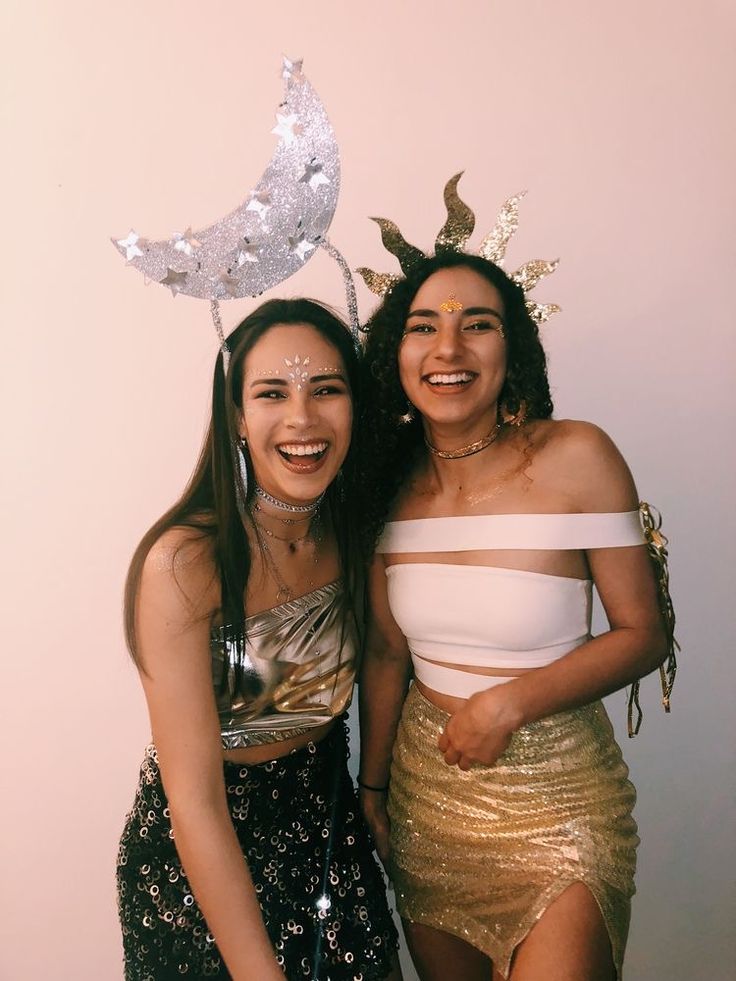 two young women standing next to each other in front of a white wall wearing costumes